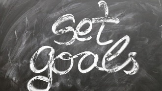 Text reading "set goals" written in chalk on blackboard