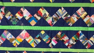 Homemade column quilt with scrappy fabrics on a blue background